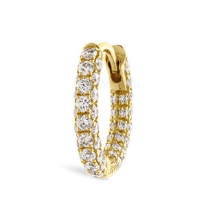 May include: A gold-colored hoop earring encrusted with multiple small, clear gemstones. The earring is a complete circle with a hinged clasp. The gemstones are closely set, creating a sparkling effect. The earring is set against a white background.
