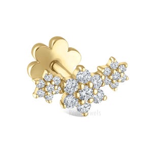 May include: A gold-colored earring with a flower-shaped base and a cluster of small, sparkling clear stones. The earring features a floral design with three clusters of stones, creating a delicate and elegant look. The earring is designed for pierced ears.