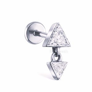 May include: A silver-colored earring with a post and two triangle-shaped pendants. The top triangle is fixed, while the bottom one dangles. The triangles have a clear, faceted appearance, suggesting they are made of a sparkling material.