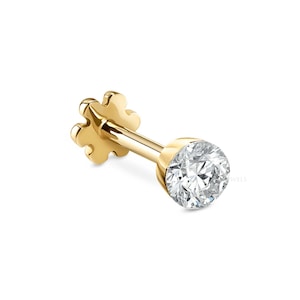 May include: A gold-colored stud earring with a clear, round gemstone. The earring has a flower-shaped backing and a straight post. The gemstone is set in a bezel setting. The earring is designed for pierced ears.