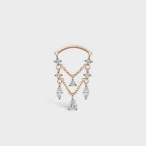 May include: A gold-toned earring with a curved top and dangling chains. The chains hold multiple clear, sparkling gemstones in various shapes, including round, marquise, and triangle cuts. The earring is designed for a single ear piercing.