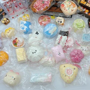 May include: An assortment of colorful, packaged, and individually wrapped miniature baked goods and candies. The collection includes various shapes and designs, such as cakes, pastries, and candies, in a variety of colors. Some items are in clear plastic packaging.