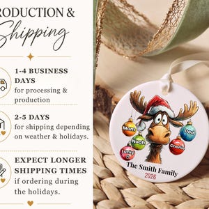 K&ouml;nnte beinhalten: Ein rundes, wei&szlig;es Keramikornament mit einem Cartoon-Elch, der eine Weihnachtsmannm&uuml;tze tr&auml;gt. Der Elch h&auml;lt bunte Weihnachtskugeln mit den Aufschriften Mom, Dad, Noah, Charlie und Lucky. Unten steht der Text The Smith Family 2026.