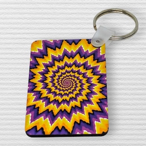 Puede incluir: Un llavero rectangular con un diseño psicodélico vibrante. La obra de arte presenta un patrón en espiral en tonos de amarillo, morado y naranja, creando una ilusión óptica. El llavero tiene un anillo de metal plateado y un accesorio de plástico blanco.