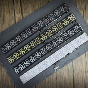 May include: Four adjustable collars featuring a repeating pentagram pattern. Three collars are black with pentagrams in iridescent, gold, and white, while the fourth is white with iridescent pentagrams. Each includes a metal buckle and a skull charm.
