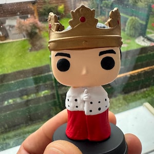 Puede incluir: Figura Funko Pop de un rey, con una corona dorada con detalles rojos, una capa blanca con lunares negros y una túnica roja. La figura está sobre una base negra y es un artículo de colección.
