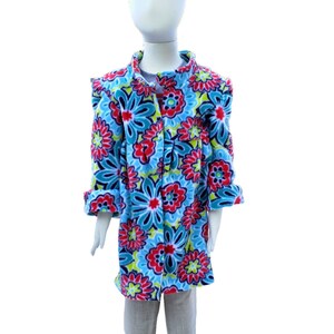 May include: A blue fleece jacket with a floral print in shades of red, green, and white. The jacket has a button closure and long sleeves.