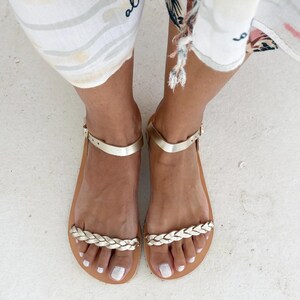 Womens gold leather barefoot sandals worn on feet, showing the comfortable fit and elegant braided strap design for a minimalist summer look.