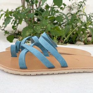 A pair o fbarefoot leather sandals with a criss-cross strap design. The sandals have a light brown leather sole and a vibram sole