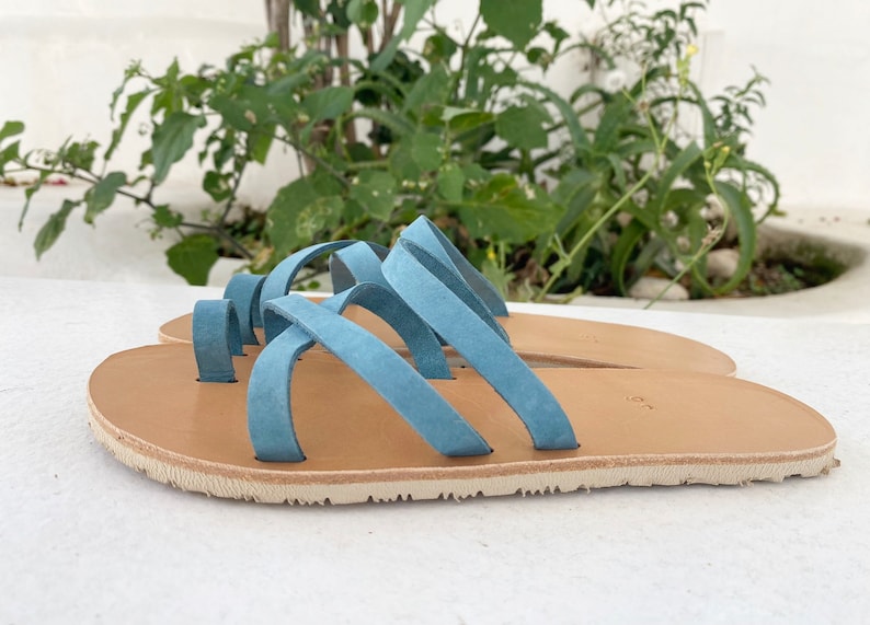 A pair o fbarefoot leather sandals with a criss-cross strap design. The sandals have a light brown leather sole and a vibram sole
