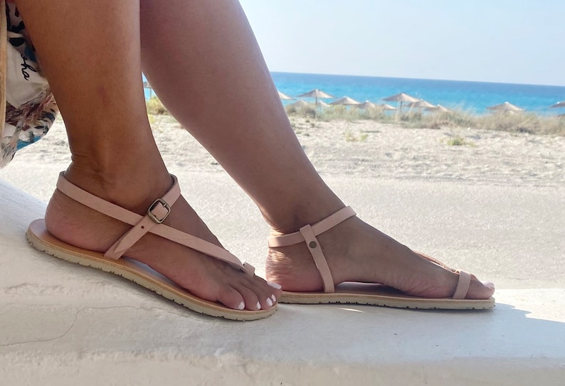 Peut inclure: Une paire de sandales en cuir rose clair avec une boucle de fermeture. Les sandales ont un design simple et sont parfaites pour l'&eacute;t&eacute;.