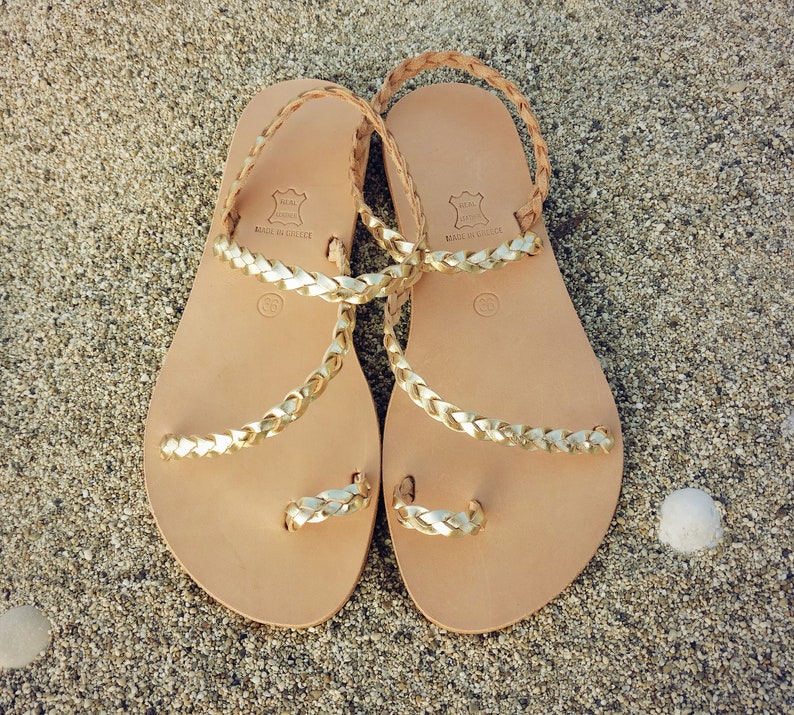 K&ouml;nnte beinhalten: Ein Paar goldene Ledersandalen mit geflochtenen Riemen. Die Sandalen sind in Griechenland hergestellt und aus echtem Leder.