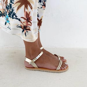 Side profile of minimalist Greek sandals on feet, showcasing the ultra-thin sole and the secure fit of the leather straps around the ankle.