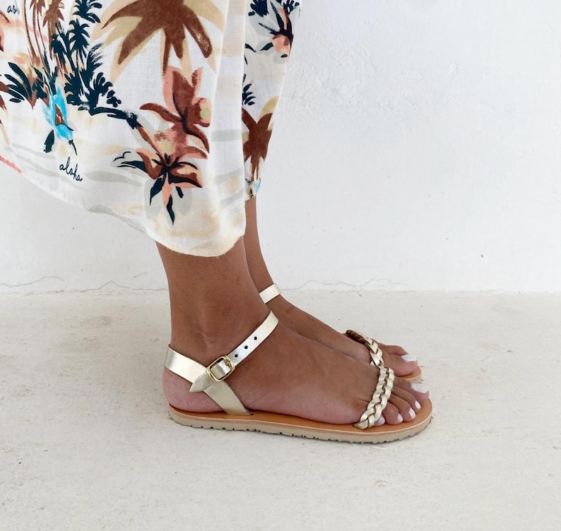 Side profile of minimalist Greek sandals on feet, showcasing the ultra-thin sole and the secure fit of the leather straps around the ankle.