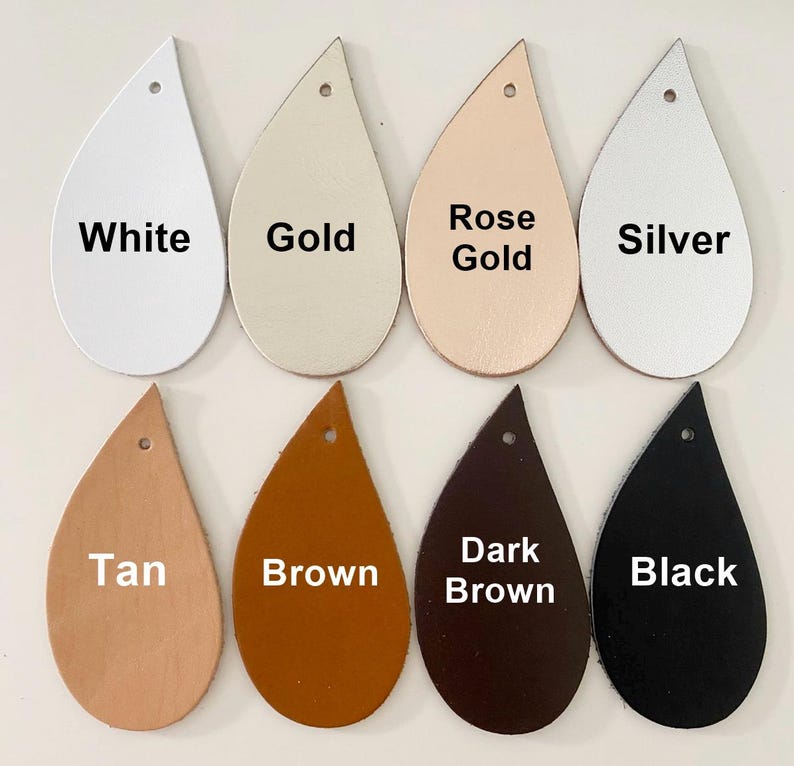 Op de afbeelding: Acht druppelvormige lederen oorbelblanco's gerangschikt in twee rijen. De bovenste rij bevat de kleuren wit, goud, ros&eacute;goud en zilver. De onderste rij toont de kleuren tan, bruin, donkerbruin en zwart. Elk stuk heeft een gaatje aan de bovenkant.