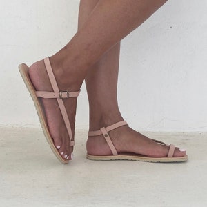 Peut inclure: Une paire de sandales en cuir rose clair avec des brides &agrave; la cheville. Les sandales ont un design simple et sont parfaites pour l'&eacute;t&eacute;.