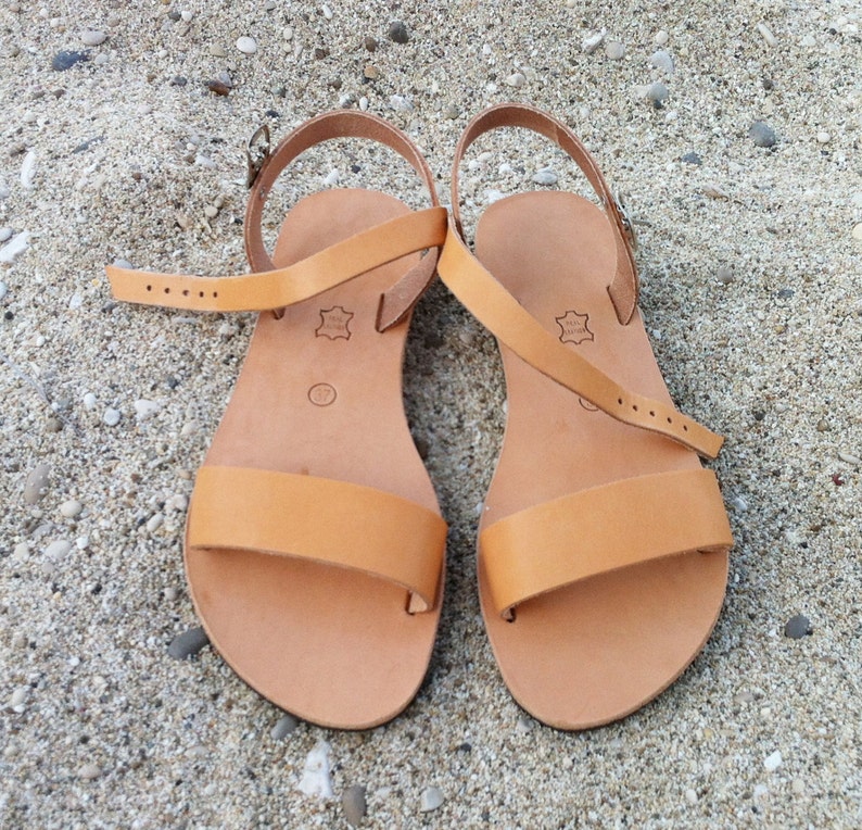 May include: A pair of tan leather sandals with adjustable straps. The sandals have a simple design and are perfect for summer.