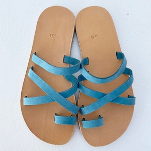 "Top-down view of a pair of handmade natural leather sandals on a neutral background, showing the anatomical shape and quality craftsmanship.