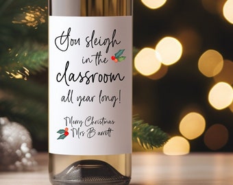 May include: A white wine bottle with a festive Christmas label that reads "You sleigh in the classroom all year long!" with a holly sprig and berries. The label also includes the text "Merry Christmas" and "Mrs. Barrett".