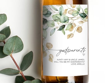 May include: A white wine bottle with a green and gold floral design label. The label reads "godparents" with the text "Aunty Amy & Uncle James, will you be my godparents? Love Arielle".