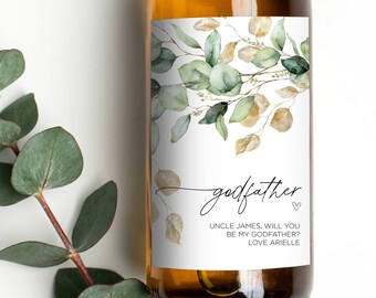 May include: A white wine bottle with a green and gold floral design label. The label reads "godfather" with the text "Uncle James, will you be my godfather? Love Arielle".