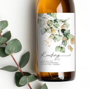 May include: A white wine bottle with a green and gold floral design label. The label reads "Reading" and "James will you read at our wedding? Love Brittany + Andrew".
