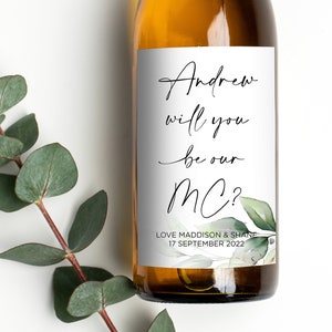 May include: A white wine bottle with a label that says "Andrew will you be our MC? Love Maddison & Smith 17 September 2022".