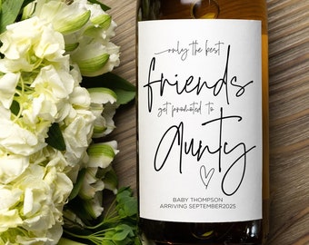 May include: White wine bottle with a label that says "Today the best friends get promoted to auntie" with a heart and the text "Baby Thompson Arriving September 2023".