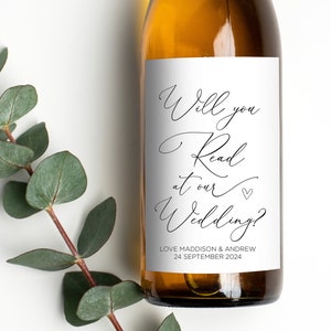May include: A white wine bottle with a label that says "Will you read at our wedding?" with the names Love Maddison & Andrew and the date 24 September 2024.