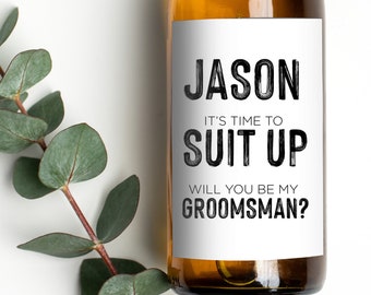 May include: A white wine bottle with a label that says "Jason It's time to Suit Up Will you be my Groomsman?"