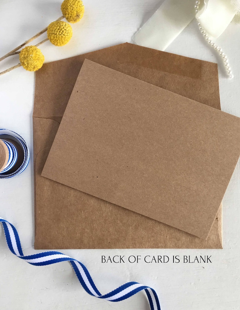 May include: A brown card with a blank back. The card is sitting on a white surface with a blue and white ribbon, a brown envelope, and yellow flowers.
