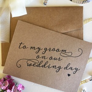 May include: A brown card with the text "to my groom on our wedding day" written in black cursive script with a small black heart at the end.