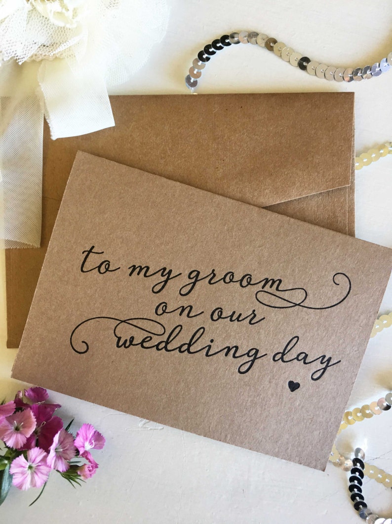 May include: A brown card with the text "to my groom on our wedding day" written in black cursive script with a small black heart at the end.