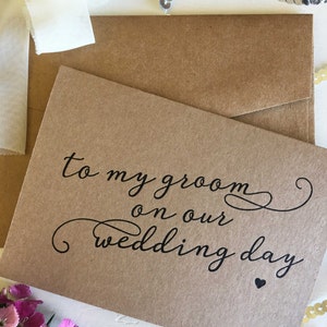May include: A brown card with the text "to my groom on our wedding day" in black cursive writing with a small black heart at the bottom.