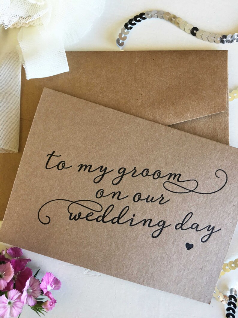 May include: A brown card with the text "to my groom on our wedding day" in black cursive writing with a small black heart at the bottom.