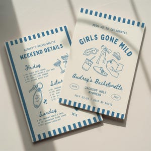 May include: Two cream-colored paper cards with blue striped borders and blue text. One card displays weekend details for Audrey's bachelorette, including a schedule from Friday to Sunday. The other card features the text Girls Gone Mild, Audrey's Bachelorette, Jackson Hole Wyoming, July 23-25, and RSVP by 06/12, with line art illustrations of a sleep mask, bow, hair clip, drink, shoe, and pants.