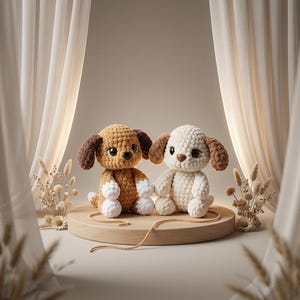 May include: Two handmade crochet dog toys. One is light brown with dark brown ears, the other is off-white with brown ears. They sit on a wooden platform with a neutral background and decorative elements.