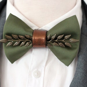 May include: A green bow tie with a bronze leaf design and a copper-colored leather accent.