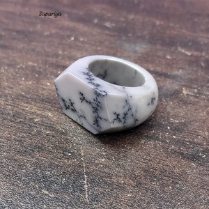 May include: A white and gray gemstone ring with a unique geometric design. The ring features a marbled pattern with black veining. The brand name "Supariya" is visible in the upper left corner. This ring is a statement piece.