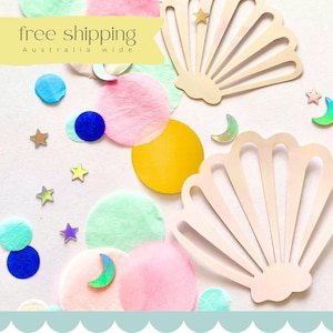 以下が含まれることがあります： パステルカラーの紙吹雪、木製の貝殻の切り抜き、星と三日月の装飾が特徴の気まぐれなアレンジメント。画像には、黄色のバナーに「free shipping Australia wide」というテキストが含まれています。