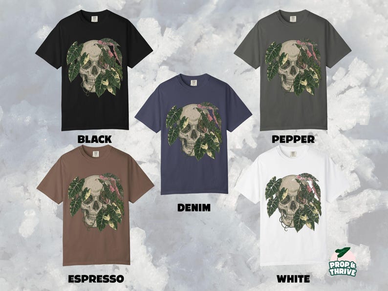 May include: Crew neck t-shirts in black, pepper, denim, espresso, and white. Each shirt features a skull design with green and pink leaves. The text "BLACK", "PEPPER", "DENIM", "ESPRESSO", and "WHITE" are displayed below each shirt.