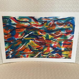 May include: Abstract painting with a vibrant mix of colors. The artwork features bold brushstrokes in shades of red, blue, orange, yellow, and green. The painting is on a white rectangular canvas, creating a dynamic and colorful composition.