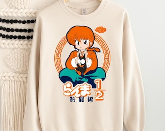 May include: Cream-colored sweatshirt featuring a cartoon character with orange hair and a black cat. The character is seated within an orange circular design with Japanese text. The sweatshirt has a crew neck and long sleeves.