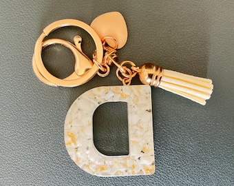 Llavero personalizado de resina con inicial, concha triturada y dije de corazón.