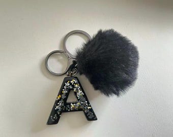 Llavero personalizado de resina con letra, colgante inicial con purpurina negra, adorno para bolso con pompón.
