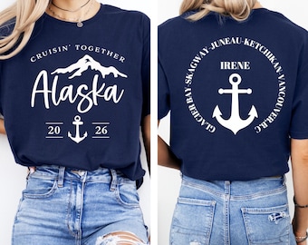 May include: Navy blue t-shirt with white text and graphics. The front of the shirt says "Cruisin' Together Alaska 2026" with a mountain and anchor design. The back of the shirt has a circular design with the name "Irene" and an anchor.
