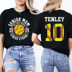 May include: Black t-shirts with softball-themed graphics. One shirt reads "SENIOR MOM THE FINAL INNING 2026 FINISH STRONG" with a softball graphic. The other shirt displays "TENLEY 10" with a softball graphic.