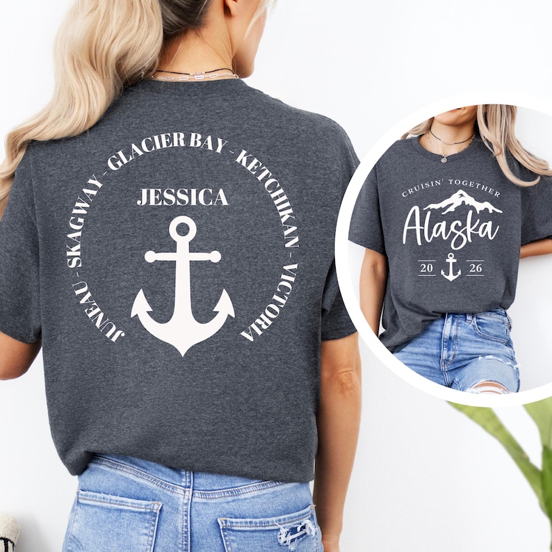 Puede incluir: Camisetas grises oscuras con dise&ntilde;os gr&aacute;ficos blancos. Una camiseta presenta un dise&ntilde;o circular con el texto "Glacier Bay, Ketchikan, Victoria, Skagway, Juneau" y un ancla. La otra camiseta dice "Cruisin' Together Alaska 20 26" con un ancla.