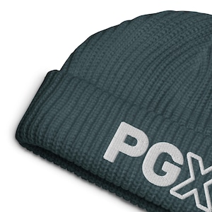 May include: A dark teal ribbed knit beanie with the white embroidered letters "PGX". The beanie is made of a soft, textured material and has a folded brim. This winter hat is a stylish accessory.