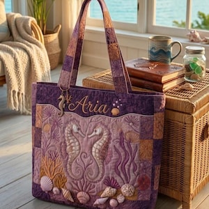 May include: A purple quilted tote bag with embroidered seahorses, seashells, and coral. The bag has a name embroidered on it, and the handles are a patchwork design. The bag is on a wooden floor.